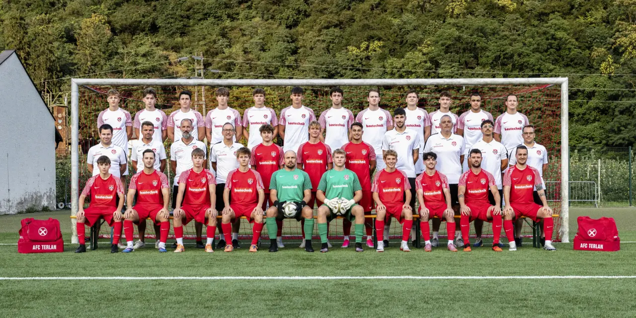 Mannschaftsfoto des AFC Terlan mit Spielern in Rot und Weiß vor einem Tor, davor Trainer und Torhüter in Grün, im Hintergrund bewaldeter Hang.