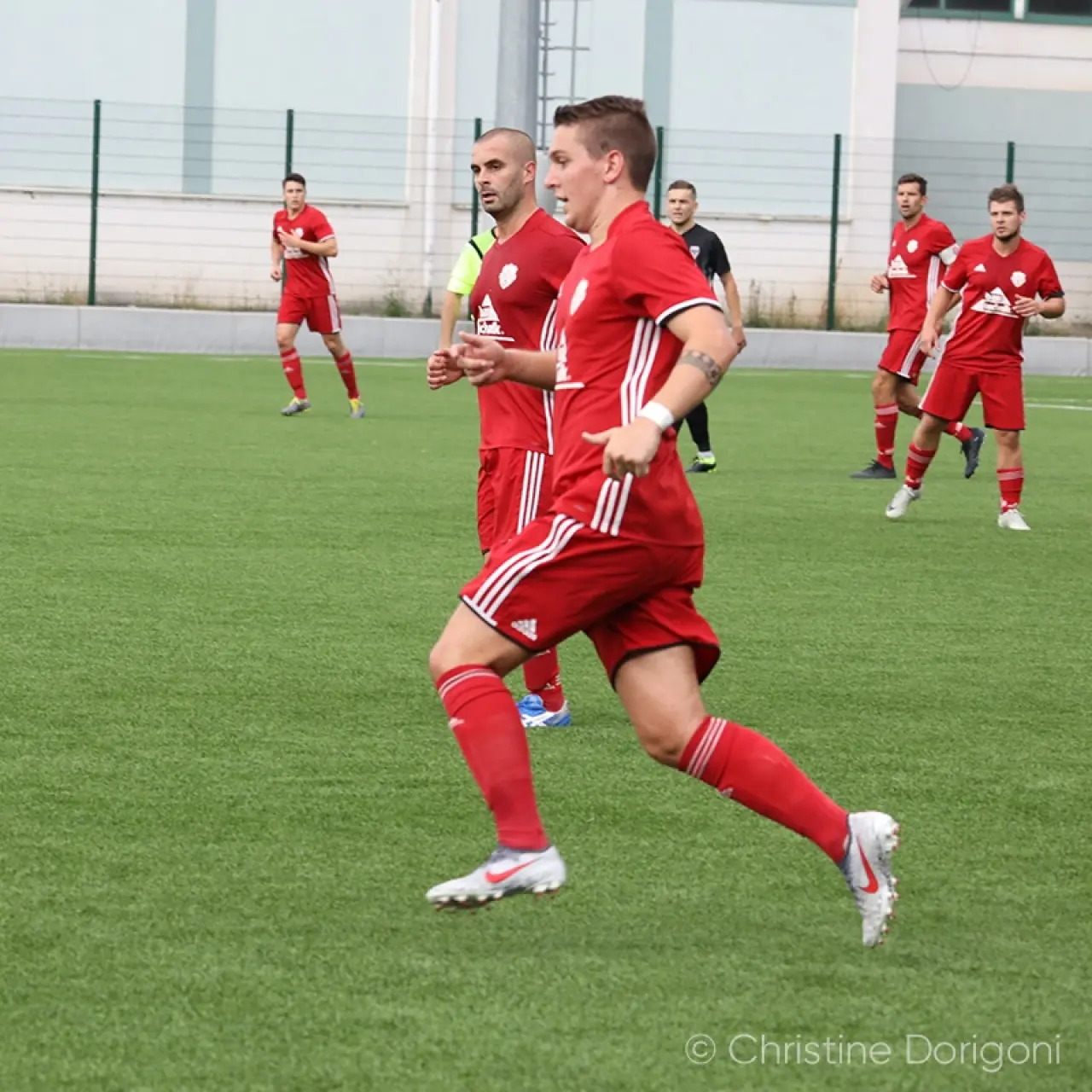 Ein Spieler in roter Trikot-Kombination läuft auf dem Kunstrasen, dahinter weitere rote und schwarz gekleidete Akteure bei einem Spiel des AFC Terlan.