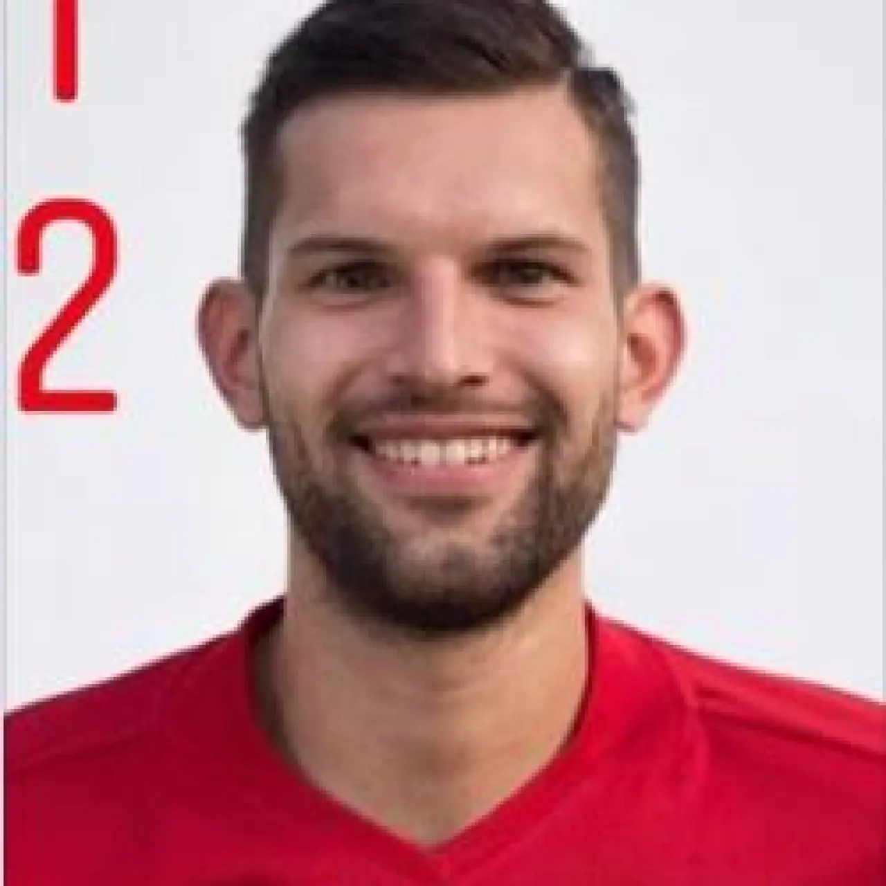 Porträt eines lächelnden Spielers des AFC Terlan im roten Trikot mit Vereinswappen und Sponsor bau technik, vor hellem Hintergrund, mit roter Rückennummer 12.