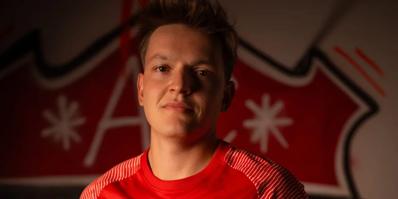 Porträt eines Spielers des AFC Terlan im roten Trikot mit Vereinswappen und Bautechnik-Sponsor vor einer Wand mit Vereinslogo.