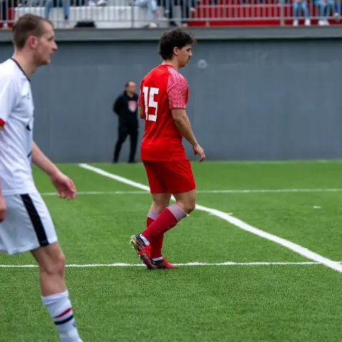 Spieler des AFC Terlan in roter Trikot mit Nummer 15 auf dem Rasen, links ein Gegenspieler in Weiß.