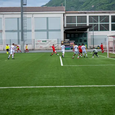 Spielszene auf dem Kunstrasen: Ein roter Angreifer zieht aufs Tor zu, während der Torhüter in Grau wartet.