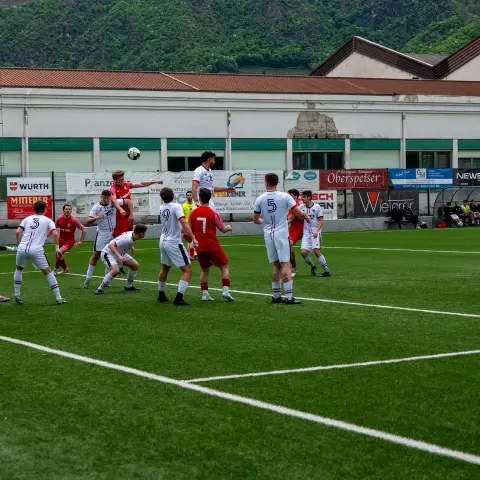 Spielszene bei einem Eckball: Mehrere Spieler in Weiß und Rot kämpfen im Strafraum um den Ball, im Hintergrund Werbebanden und Tribüne.