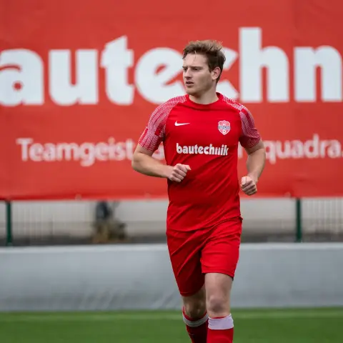 Spieler des AFC Terlan in roter Trainingskleidung läuft über den Platz vor einer roten Bande mit dem Schriftzug bautechnik.
