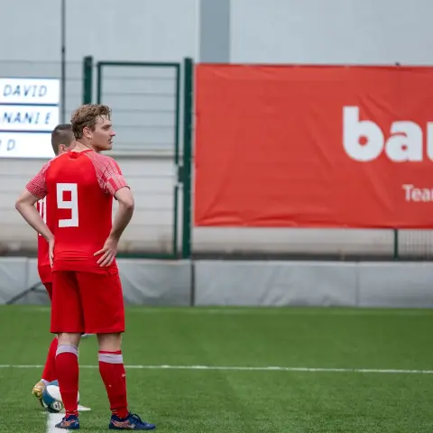 Spieler des AFC Terlan in roter Trikotnummer 9 steht auf dem Kunstrasen, im Hintergrund Anzeigetafel mit Spielernamen und Werbebanner.