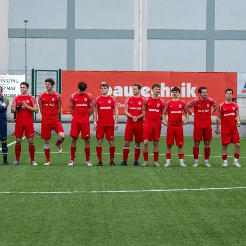Die Mannschaft des AFC Terlan in roten Trikots steht vor dem Spiel in einer Reihe auf dem Rasen, im Hintergrund die Bande mit Bautechnik-Werbung.