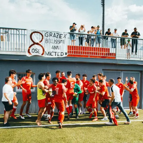 Spieler des AFC Terlan in roten Trikots jubeln nach einem Sieg auf dem Rasen, darüber ein Banner mit dem Schriftzug "8 Jahre - Grazie x Bellissimi anni" und Zuschauern auf der Tribüne.