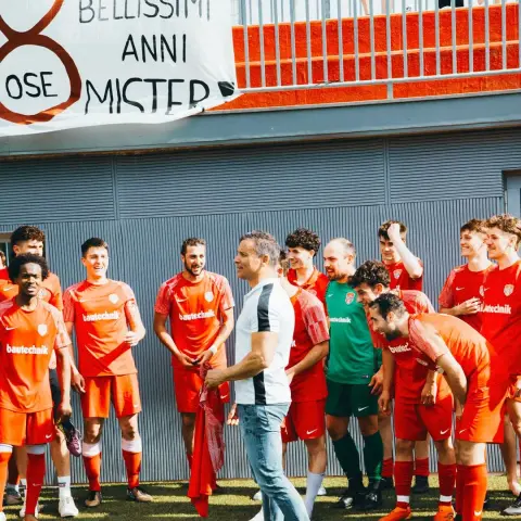 AFC-Terlan-Spieler in orangen Trikots verabschieden ihren Trainer mit dem Banner „Grazie x bellissimi 8 anni mister“.