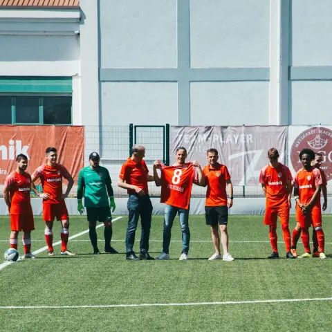 Spieler des AFC Terlan in roten Trikots auf dem Rasen, ein Mann hält ein rotes Trikot mit der Nummer 8 in die Höhe.